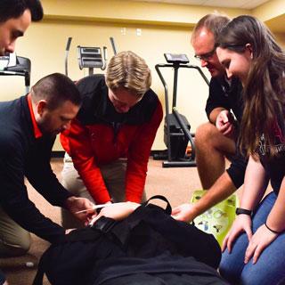 健康, 健康, 和运动科学学生练习急救, 和一个同学在担架上摆姿势